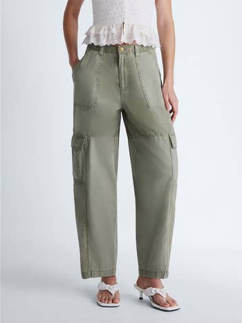 Person wearing relaxed-fit cargo pants and a sleeveless top, hands in pockets. They stand against a plain background