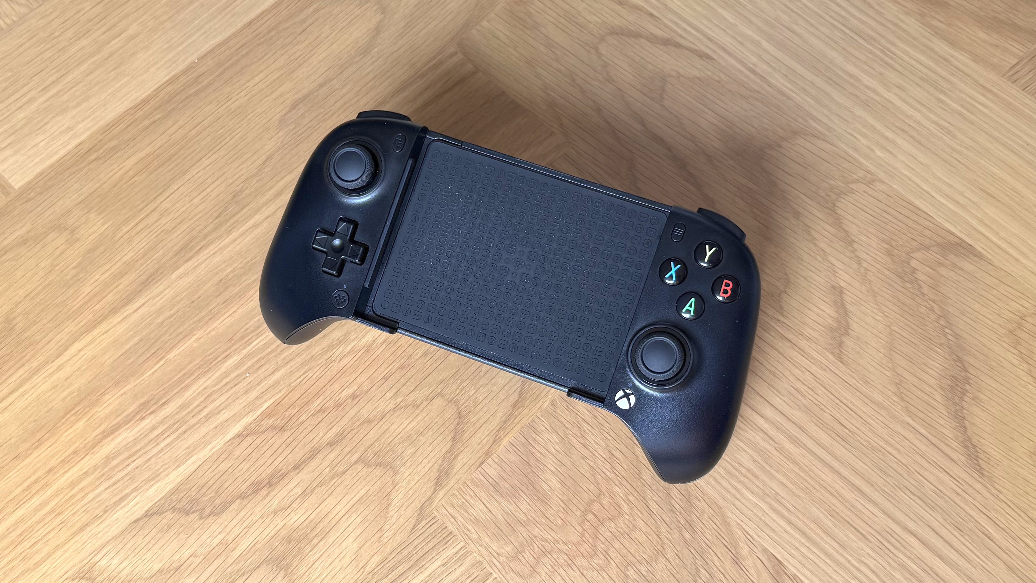 The 8BitDo Ultimate Mobile Gaming Controller - Xbox Edition with the background of a wooden surface.