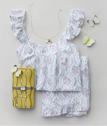 Floral-patterned outfit set paired with a yellow clutch wallet, delicate necklace, and butterfly accents
