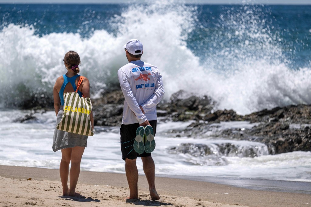 beachgoers-stop-watch-waves-crash-135222414