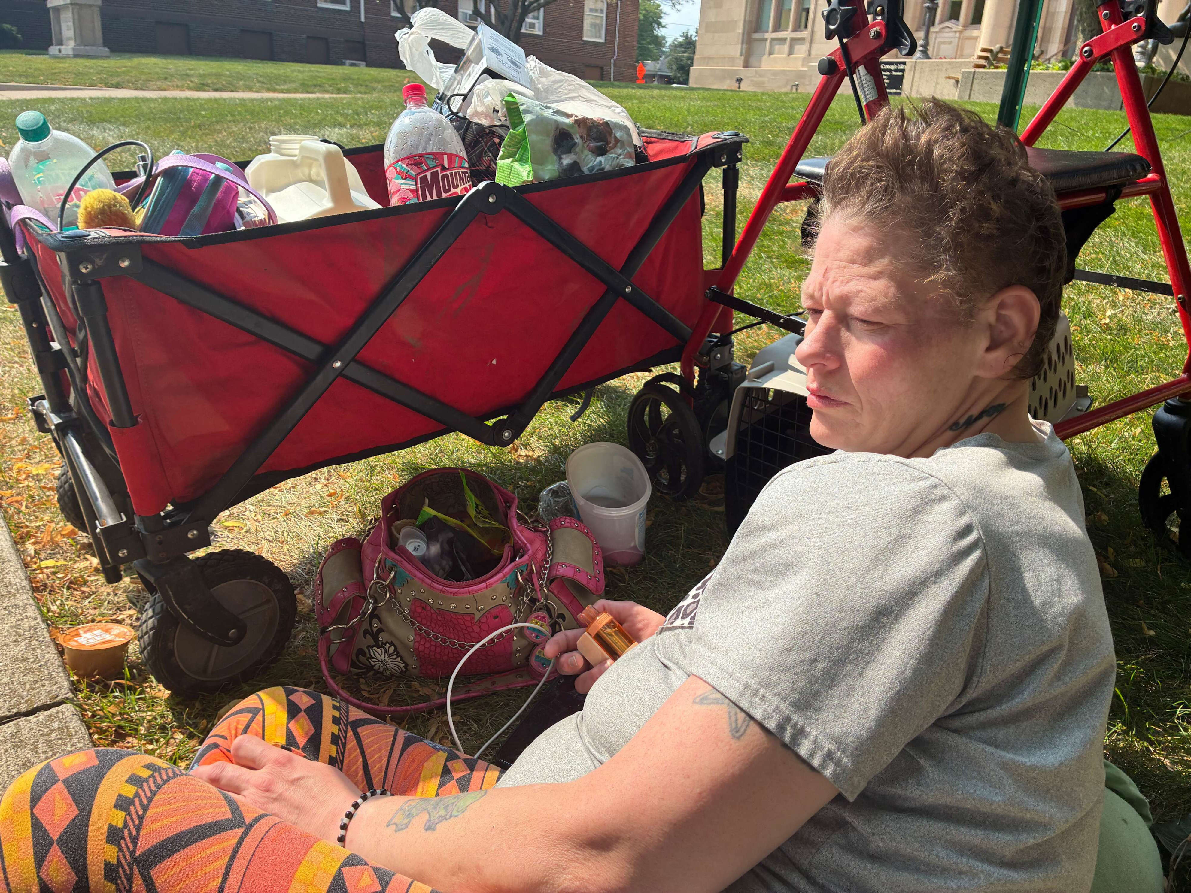Krista Toothman, 47, rests in the grass Tuesday, July 22, outside the downtown Jackson District Library. She had no place to go. She was staying with her boyfriend at nearby Reed Manor until he suddenly died.
