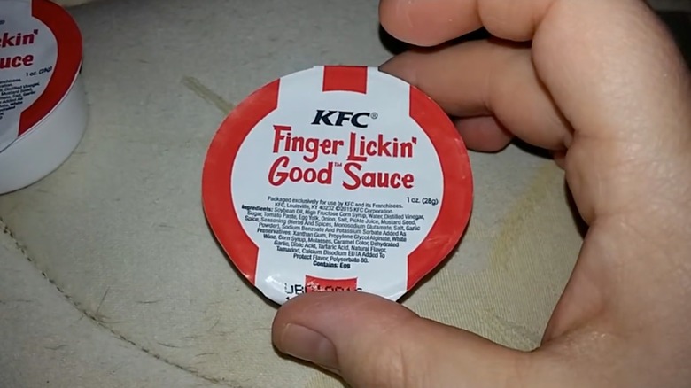 Hand holding package of KFC Finger Lickin' Good sauce