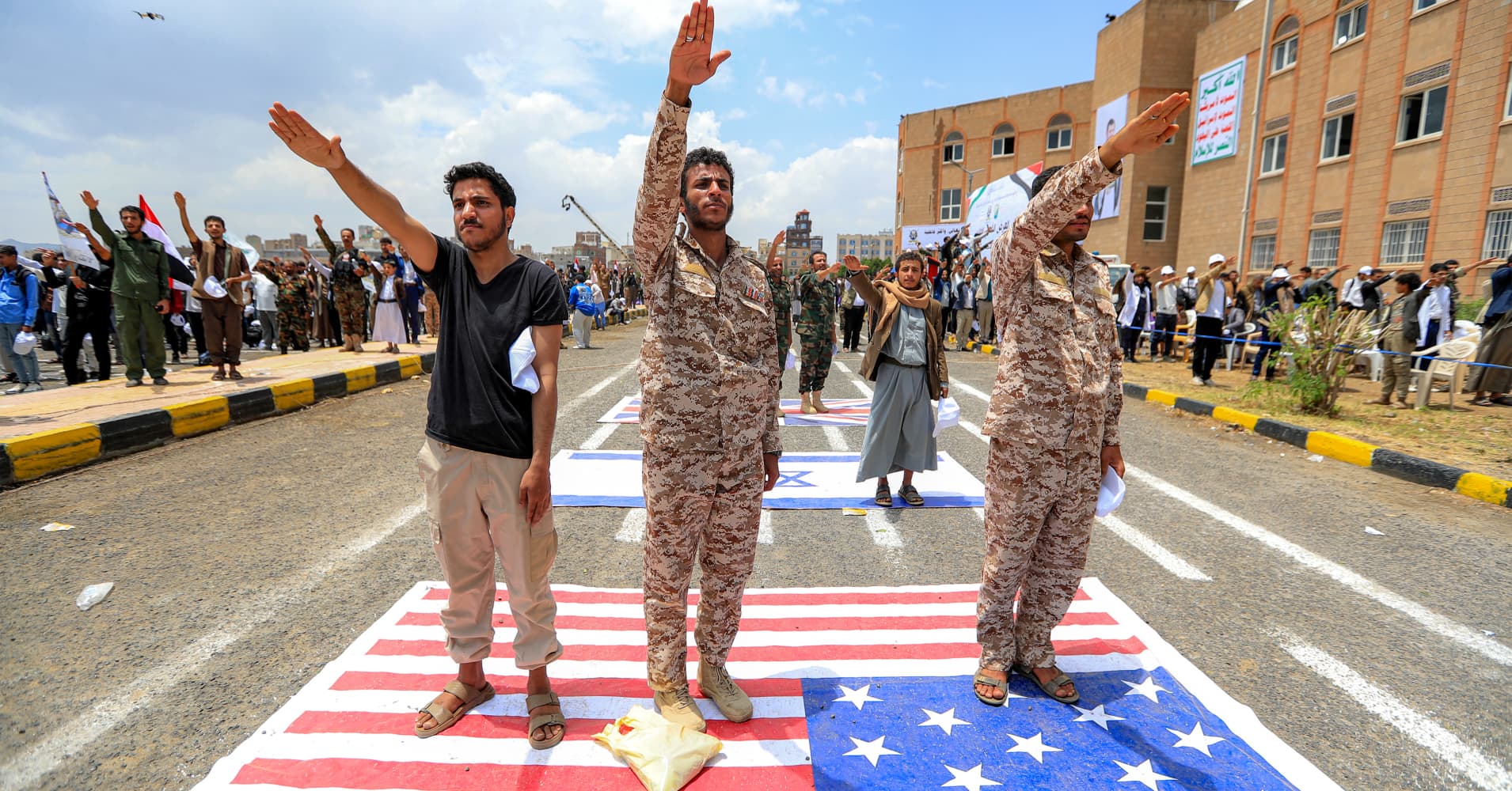 Men give a salute while standing over a depiction of the US flag during a demonstration by university students to show their support for the Houthi movement amid escalating tensions with Saudi Arabia, at the Sanaa University campus in Yemen's Houthi-held capital Sanaa on July 22, 2026.
