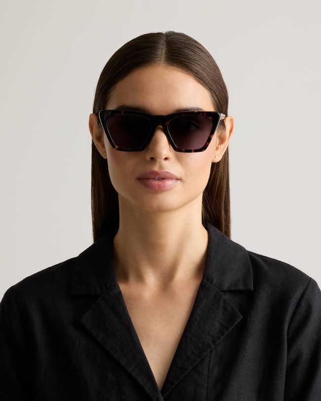 Person wearing stylish sunglasses and a black blazer, posing confidently