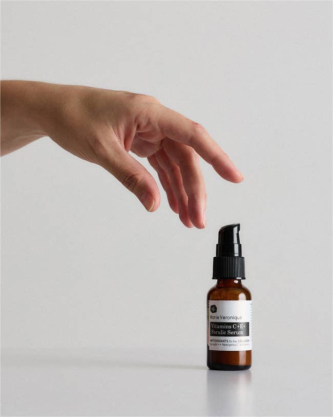 Hand reaching for a bottle of Marie Veronique Vitamin C+E Ferulic Serum, featured in a shopping article