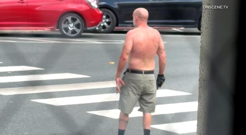 A shirtless, bald man standing in the street