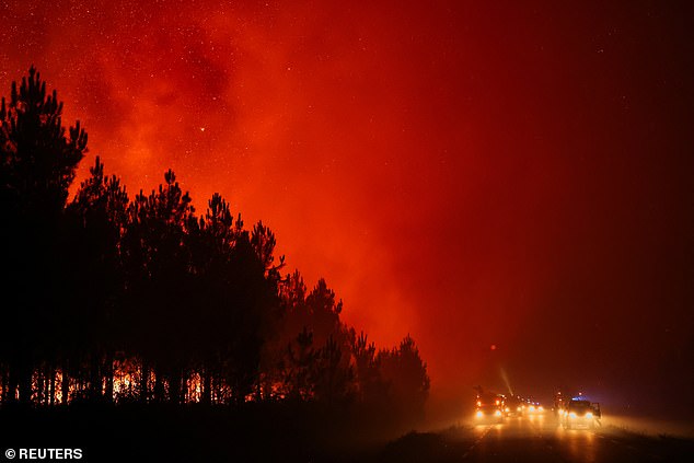 Vehicles drive by in Le Porge as a wildfire burns in a forest area in the Gironde department, as drought conditions worsen following a heatwave and water shortages across much of France, July 22