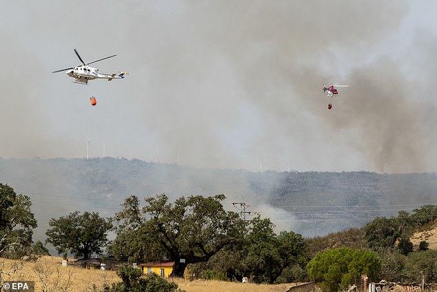 Fire-fighting helicopters work to extinguish a fire that broke out late July 21 at El Cerro del Andevalo (Huelva), Spain