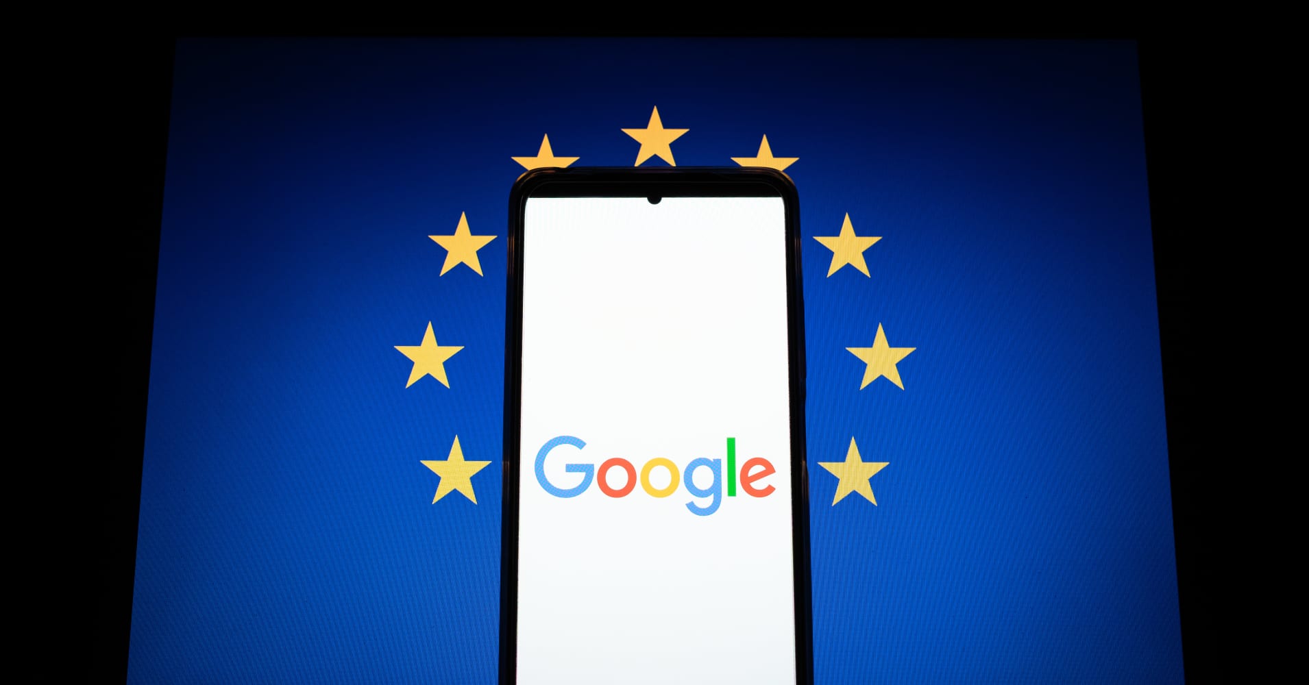 A Google logo displays on a smartphone screen and the European flag on a computer screen.