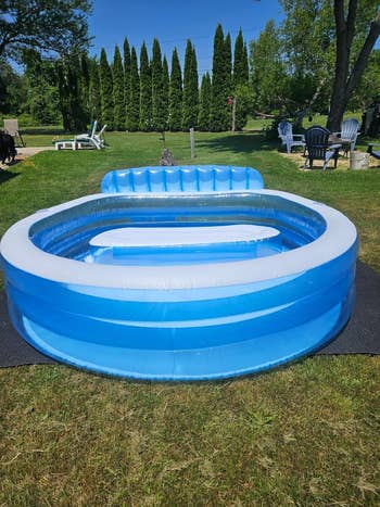 Inflatable outdoor pool on reviewer's grassy lawn, with built-in bench and backrest