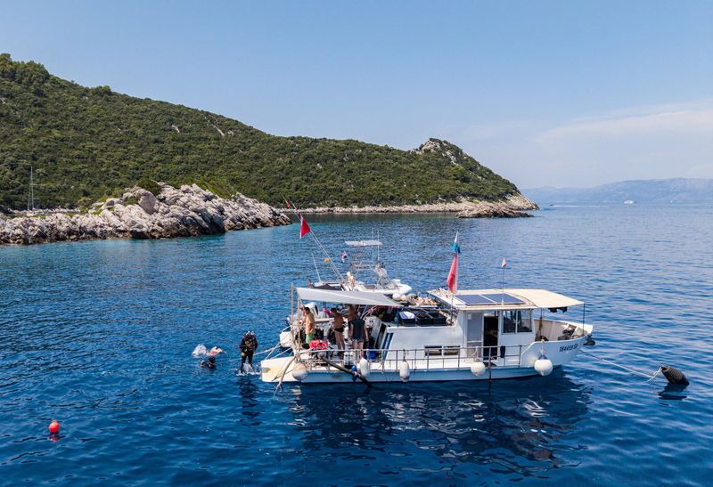 A drone view shows an underwater archaeologist jumping from a ship to the location where a Byzantine shipwreck was found near Polace on the island of Mljet