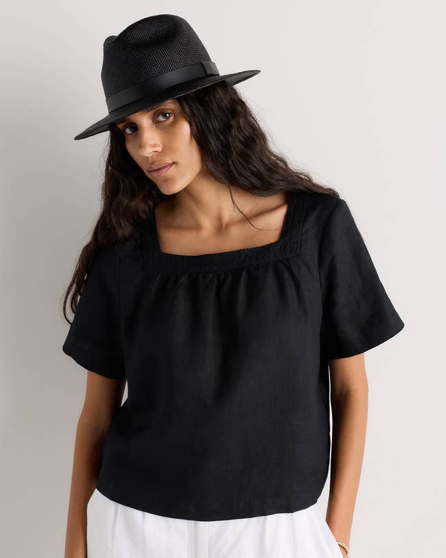 Person wearing a stylish square-neck black top and a textured hat