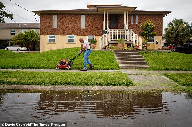 Clarence Hebert, 69, was seen mowing his lawn as winds from Tropical Storm Bertha push water into the street just after the morning high tide in Venetian Isles, Louisiana on Wednesday