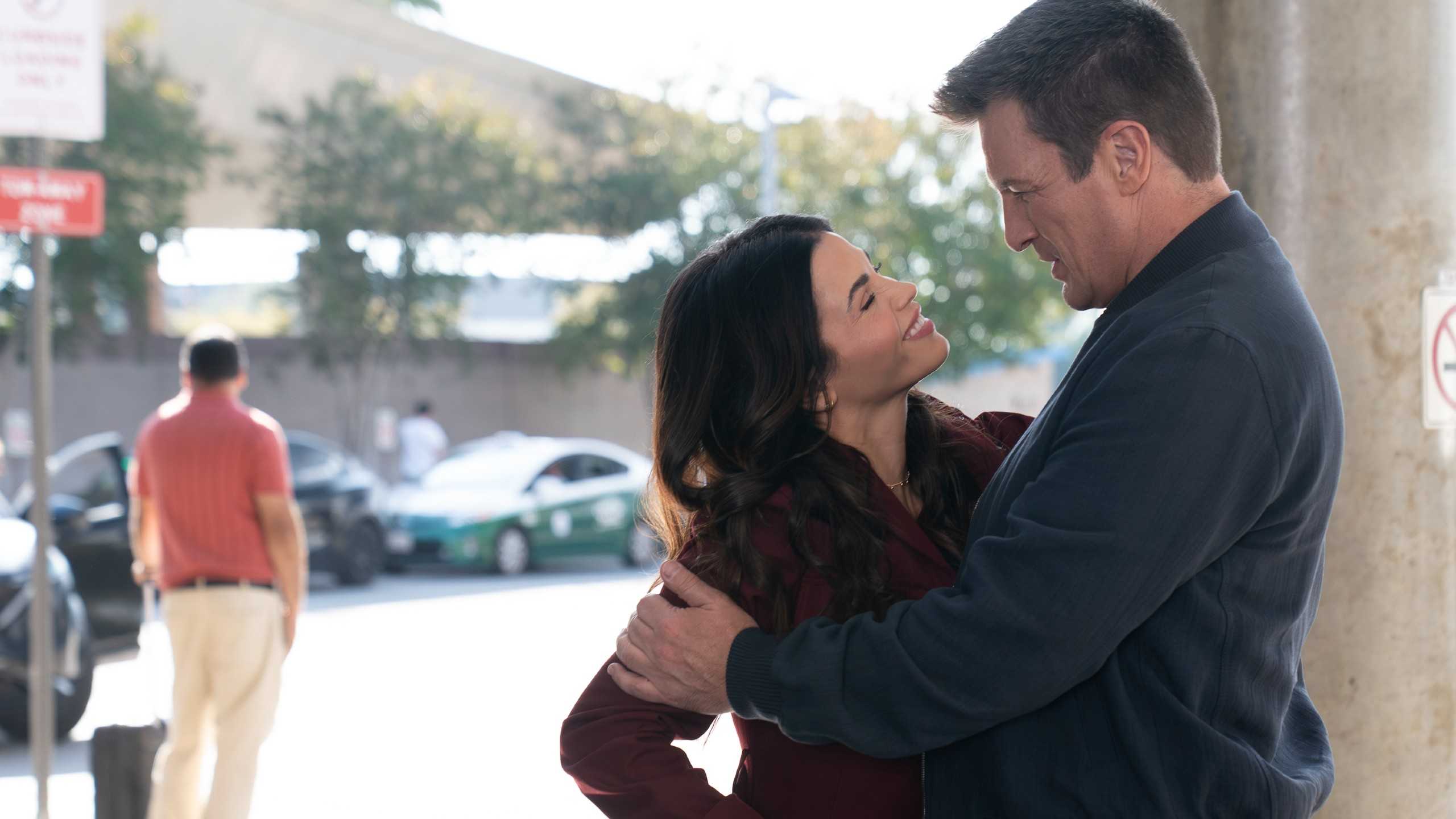 The Rookie still featuring Bailey Nune and John Nolan smiling at one another in a parking lot.