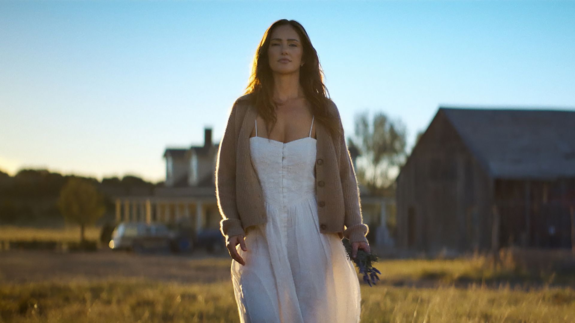 Quinn stands in a field in front of a barn