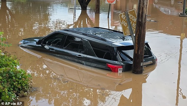A vehicle is seen sitting half-submerged in floodwaters in Buckhannon, West Virginia