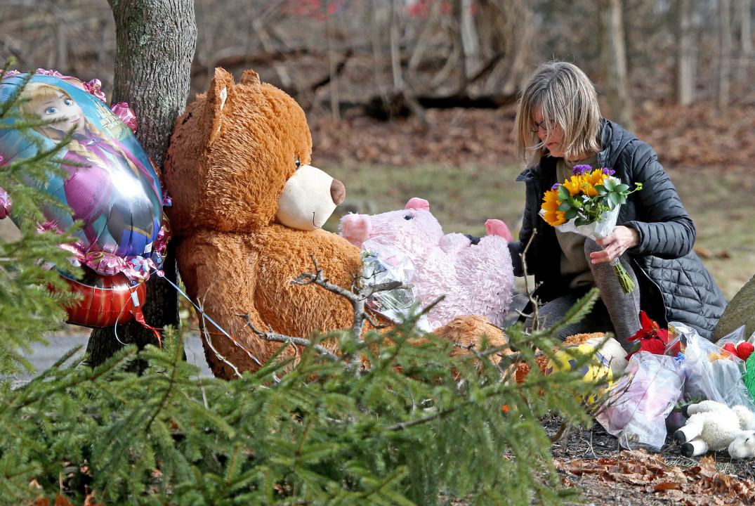 A woman lays flowers down at a makeshift memorial