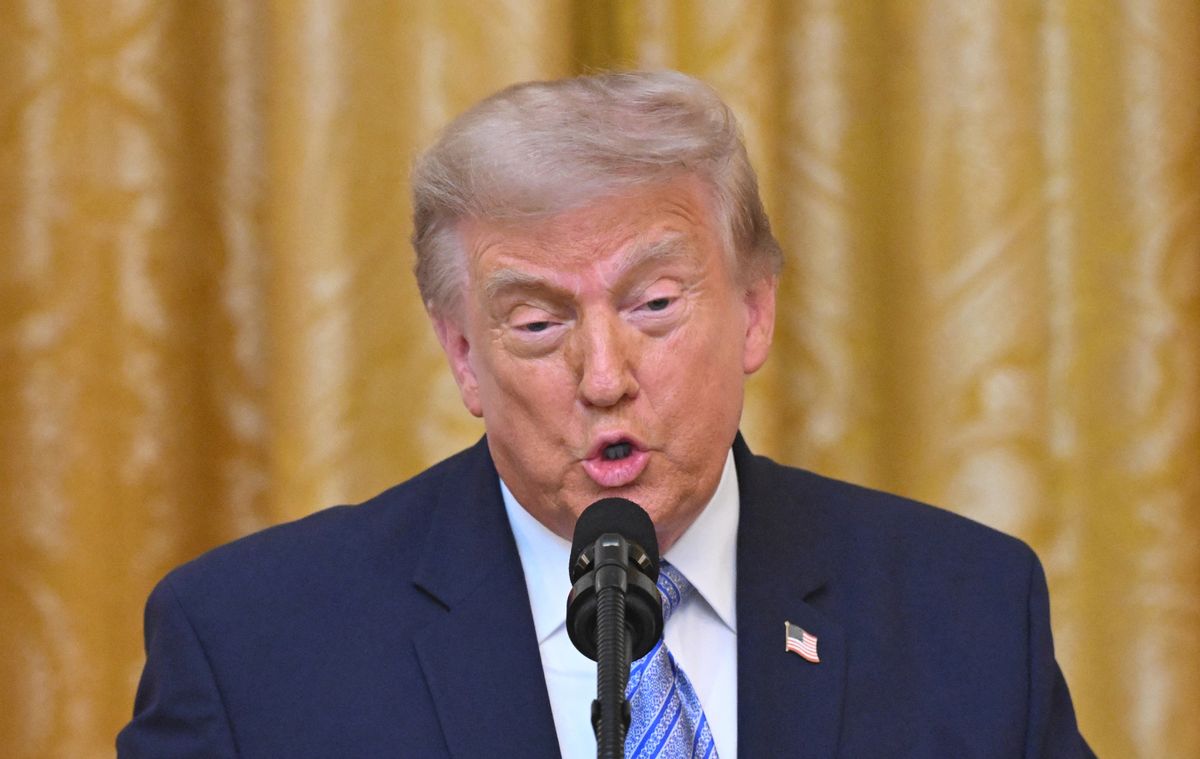 Trump speaks into a microphone. The background is a yellow curtain. Saul Loeb, via Getty Images