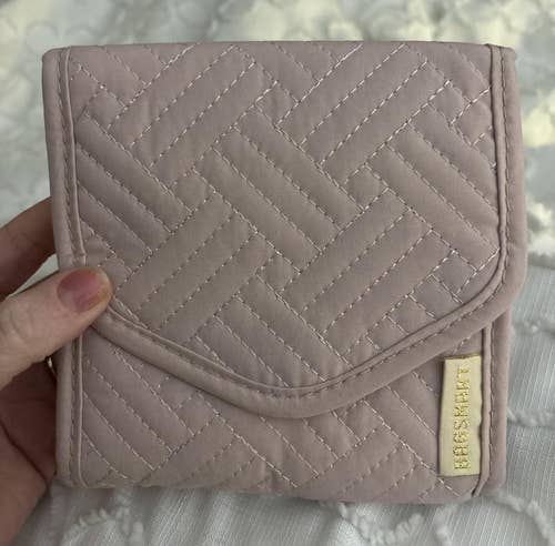Hand holding a small, textured quilted case with a geometric pattern