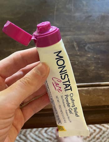 Hand holding a tube of Monistat Chafing Relief Powder Gel with an open cap, used for soothing and protecting skin
