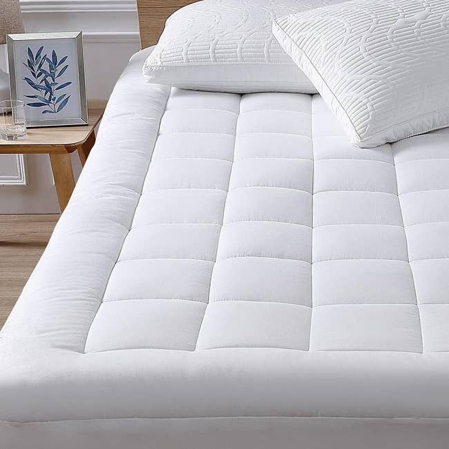 Plush, quilted mattress topper with a pillow on a bed