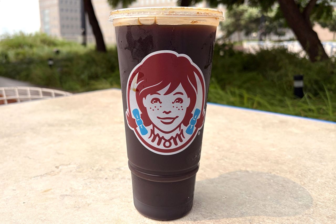 A cup of iced coffee from Wendys placed outdoors with the logo visible on the cup