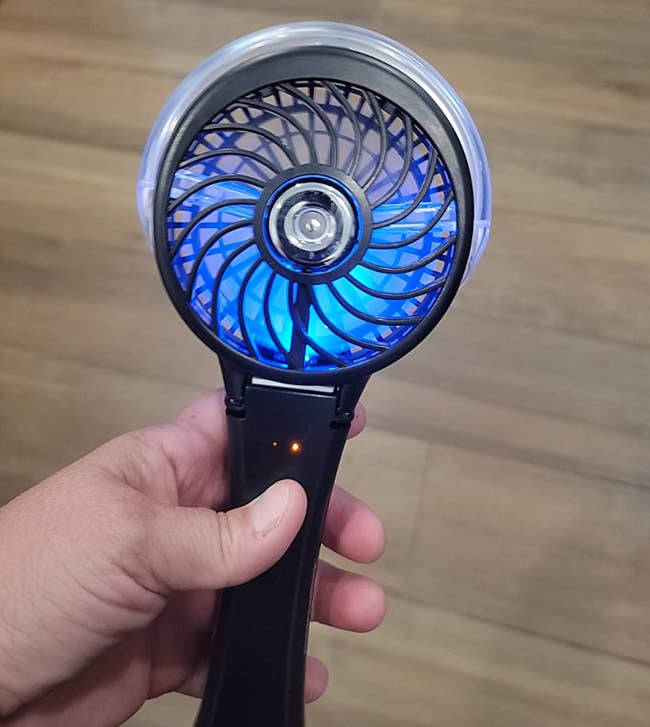 a reviewer holding their black portable fan