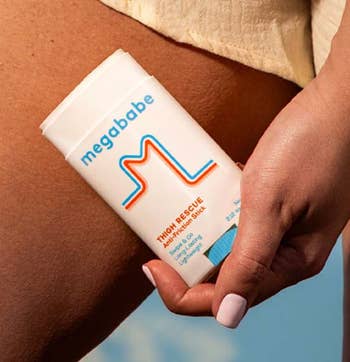Person applying Megababe Thigh Rescue anti-chafe stick to their thigh, featured in a shopping article