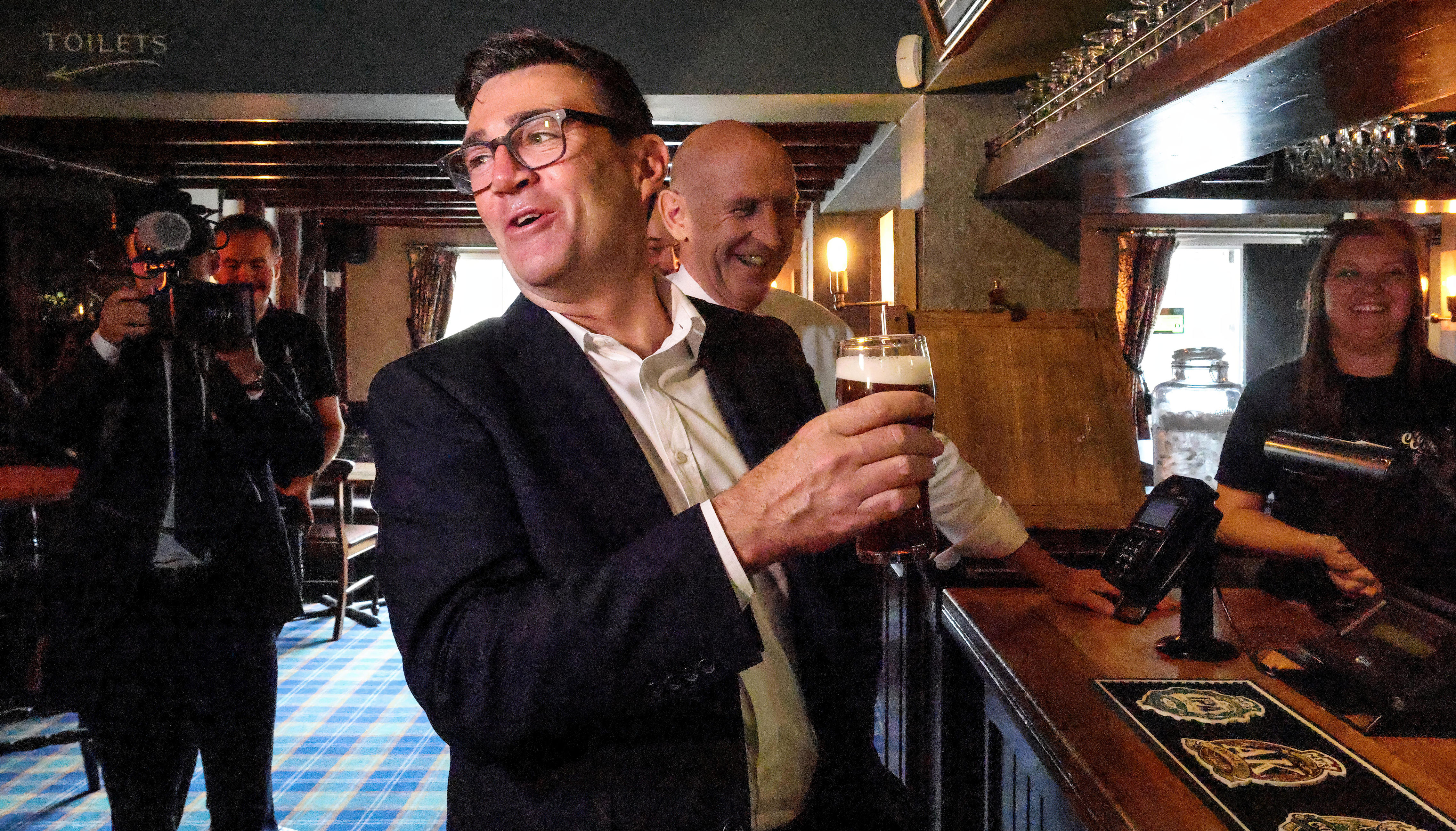 Prime Minister Andy Burnham reacts while holding a pint of beer as he visits the Hare Inn in Harlow, Essex (Getty)