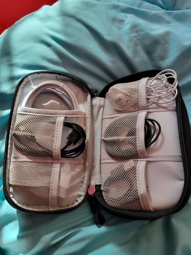 Open travel organizer with various electronic cables and chargers neatly stored in mesh pockets
