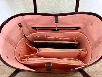Open designer handbag with compartments, showcasing spacious interior and organizing pockets