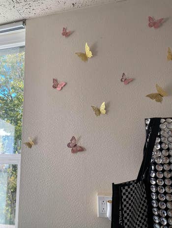 The butterflies in pink and gold stuck to the white wall of a home
