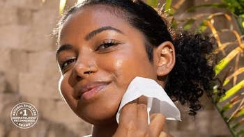 Person using a facial wipe with a small emblem reading