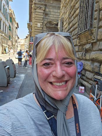 Person smiling while walking on a city street, wearing a cooling towel and a striped top.