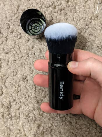 Hand holding retractable makeup brush