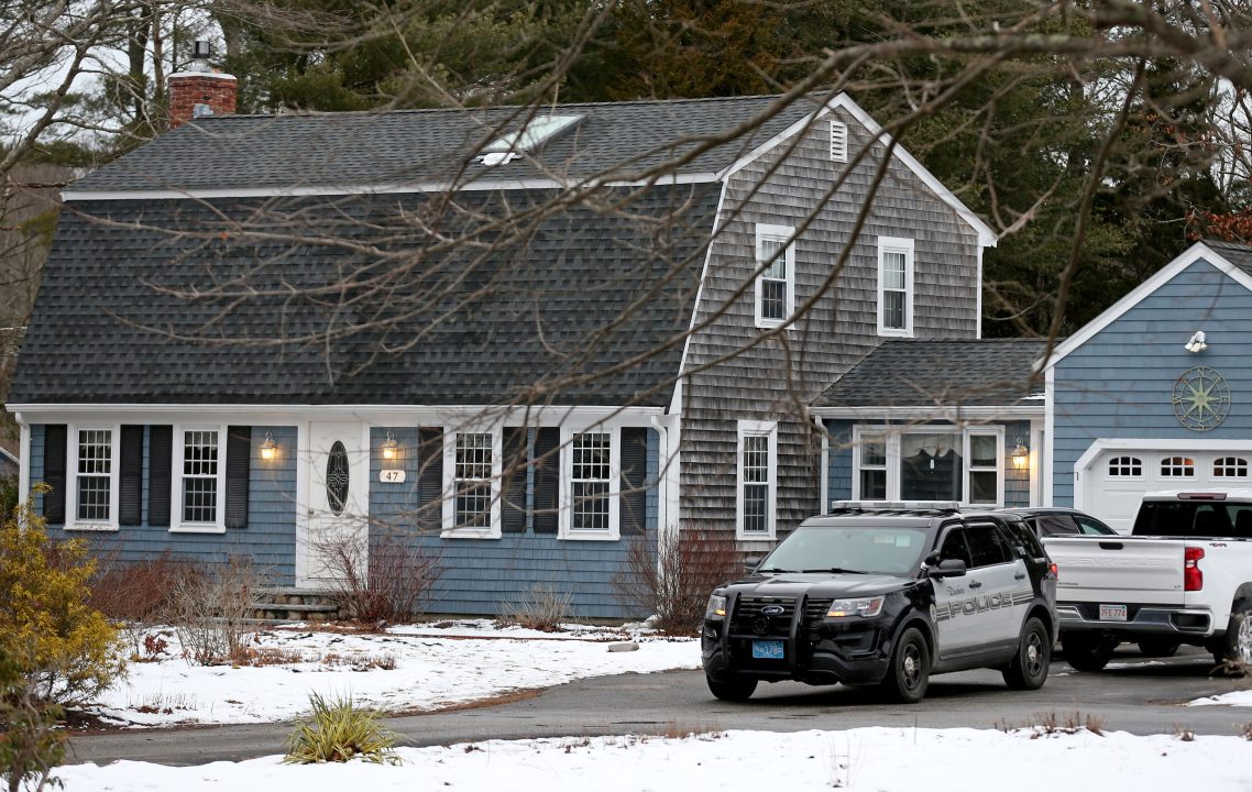 A police cruiser sits in the driveway of the blue home