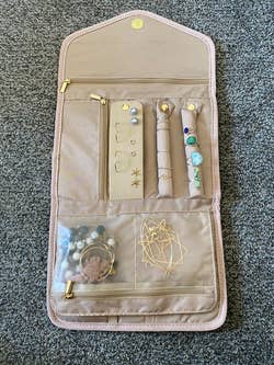 Travel jewelry organizer with compartments, holding earrings, rings, and necklaces