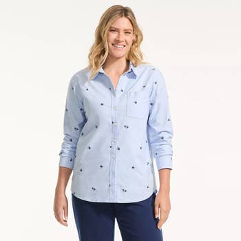 Person smiling in a casual button-up shirt with embroidered pattern and blue pants, featured for a shopping article
