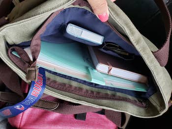 Open bag reveals notebooks, a closed book, and a pack of tissues.