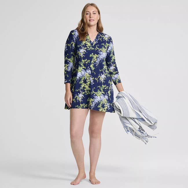 Person modeling a floral long-sleeve dress, holding a striped towel. Fashion emphasized for shopping context