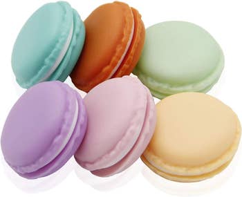Six pastel macarons displayed in a circular arrangement on a white surface