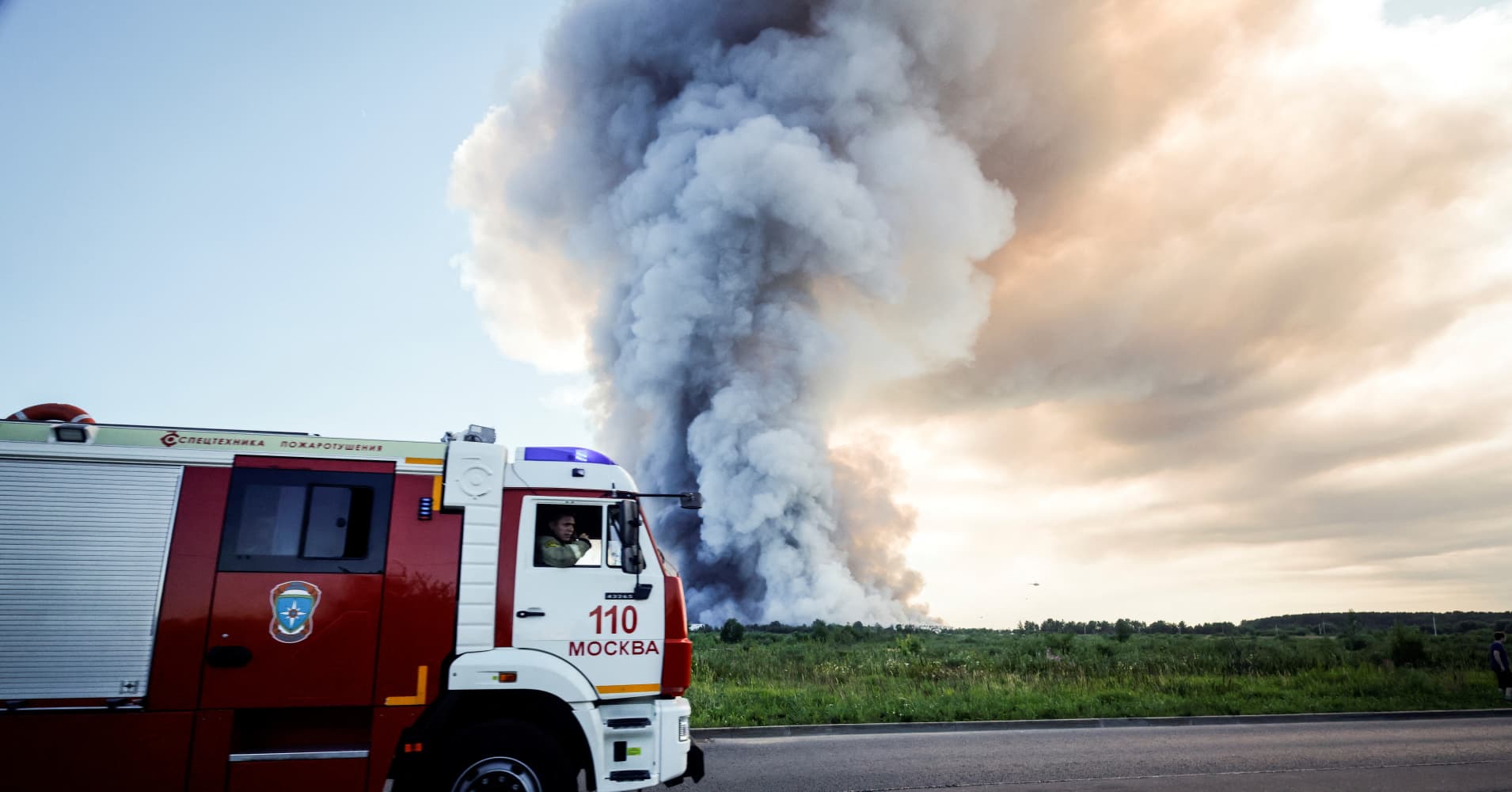 Firefighters drive past the smoke of a fire at the Russian e-commerce firm Wildberries' logistics complexes in the town of Elektrostal outside Moscow on July 18, 2026. A Ukrainian drone attack on two logistics centres in Russia killed eight people and injured 24, officials said on July 18, 2026.
