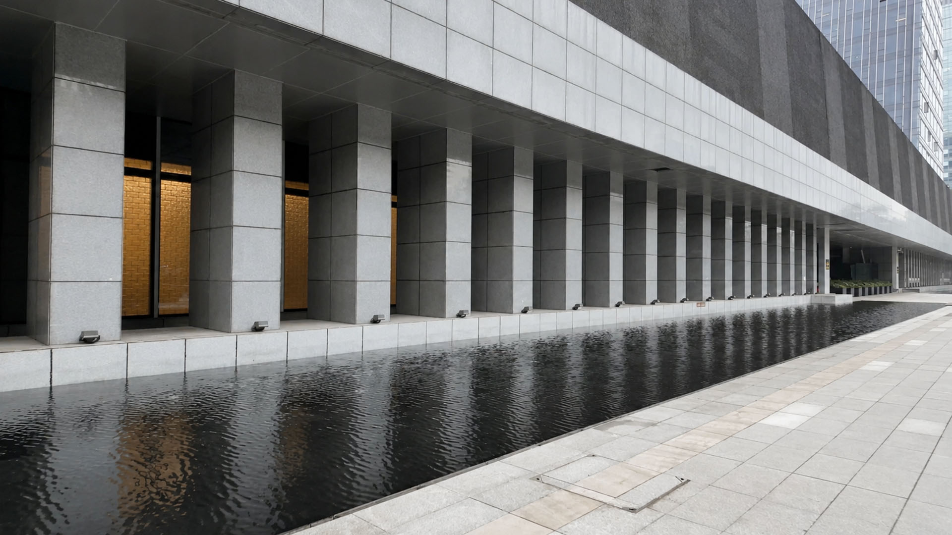 A contemporary building features endless columns above a reflecting ...