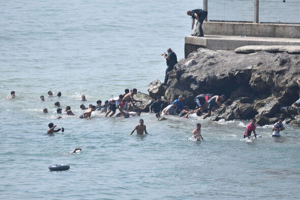 Hundreds Of People Are Swimming Across To Ceuta From Morocco, With A Crowd Waiting On The Other Side Of The Border