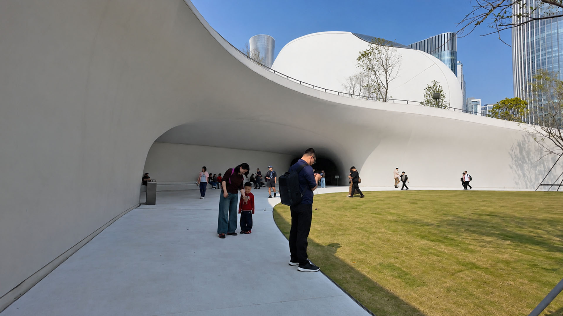 Curved white architecture frames an open green courtyard in urban China