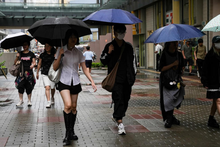 Hongkongers walk in rain in July 2026 . Photo: Kyle Lam/HKFP.