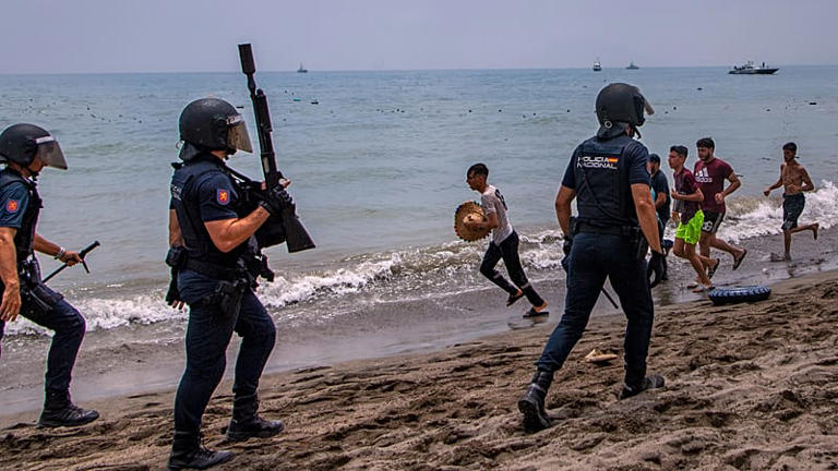 Spanish police officers intervene as migrants cross from Morocco into the Spanish enclave of Ceuta on 30 July 2026.