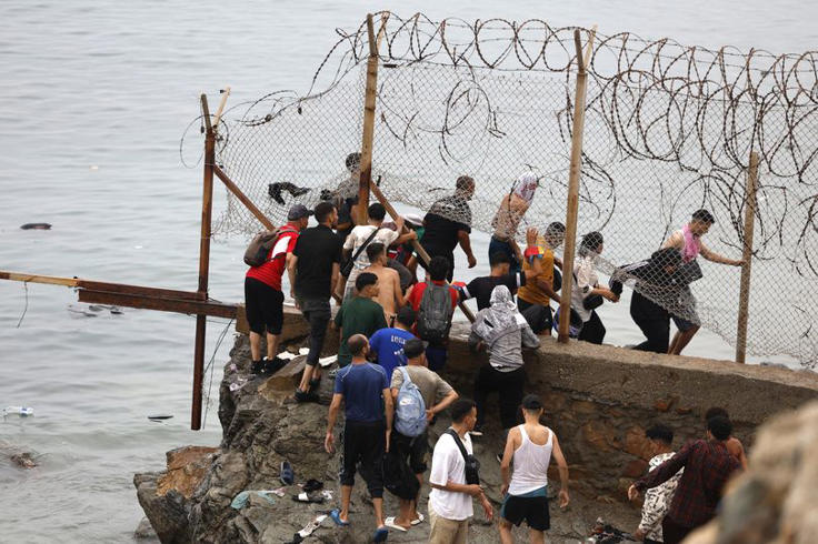 People gather along the fence close to the site of clashes near Fnideq, on the Morocco-Spain border, on July 31, 2026