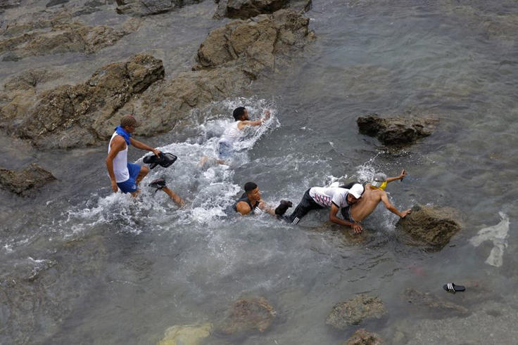 People try to swim through the waters close to the fence near Fnideq, on the Morocco-Spain border, on July 31, 2026