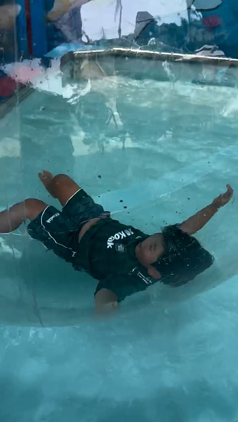 Kid plays in inflatable ball in pool